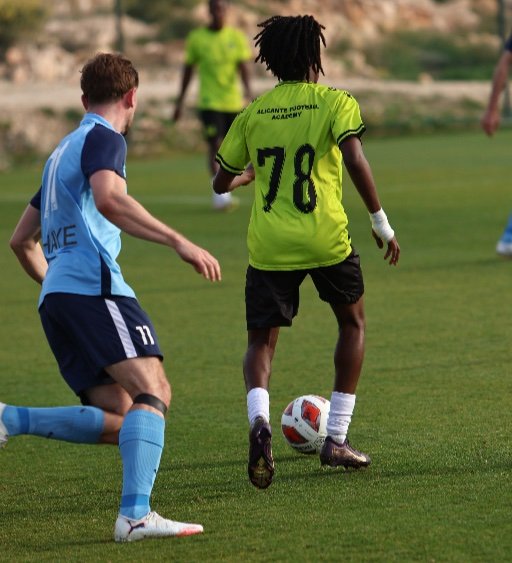 alicante football academy player number 78 dribbles the ball as a blue defender closes in