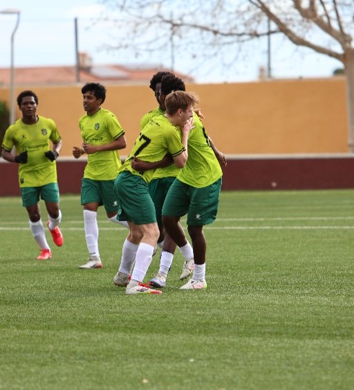 alicante football academy players celebrating together on the pitch