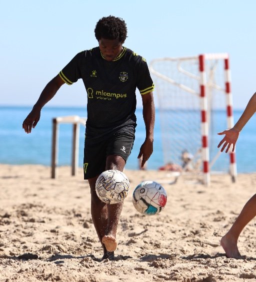 kid juggling football on beach at alicante football academy